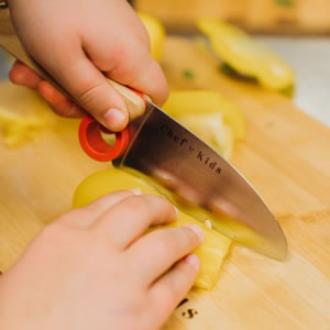 Een kind snijd groentes met een opinel mes